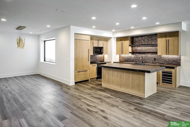 kitchen with range with gas cooktop, black microwave, wine cooler, wood finished floors, and paneled fridge