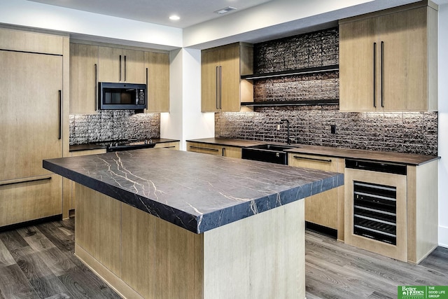 kitchen featuring paneled fridge, dark wood-type flooring, beverage cooler, a sink, and black microwave