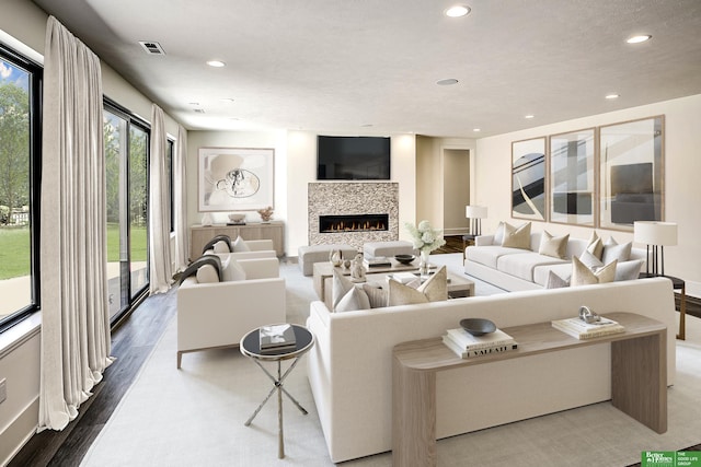 living area featuring visible vents, recessed lighting, a lit fireplace, and wood finished floors