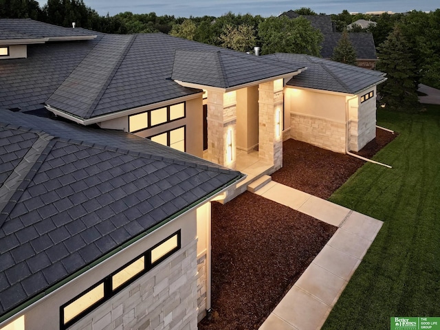 view of property exterior with stucco siding, stone siding, and a lawn