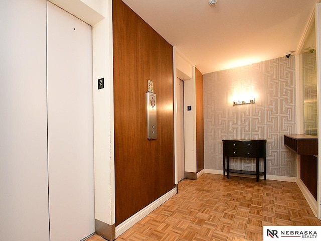 hall featuring baseboards, elevator, and wallpapered walls