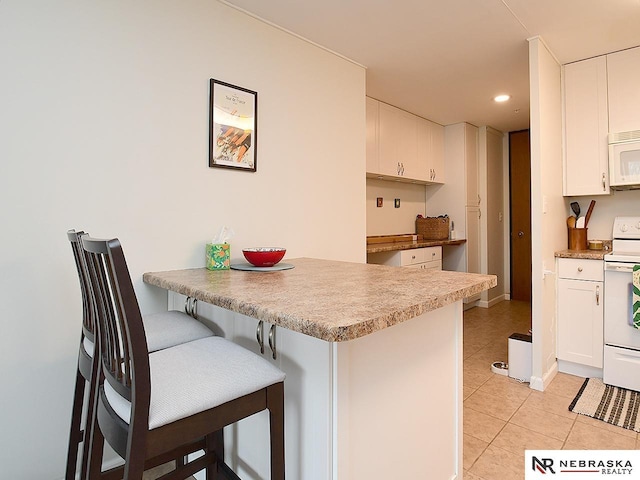 kitchen featuring light tile patterned floors, white appliances, a peninsula, and white cabinetry