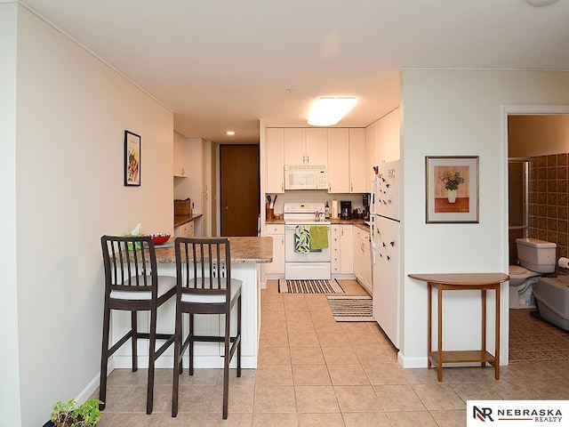 kitchen featuring white appliances, a peninsula, light tile patterned flooring, and white cabinetry