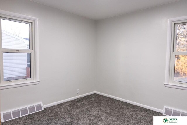 unfurnished room with visible vents, dark carpet, and baseboards