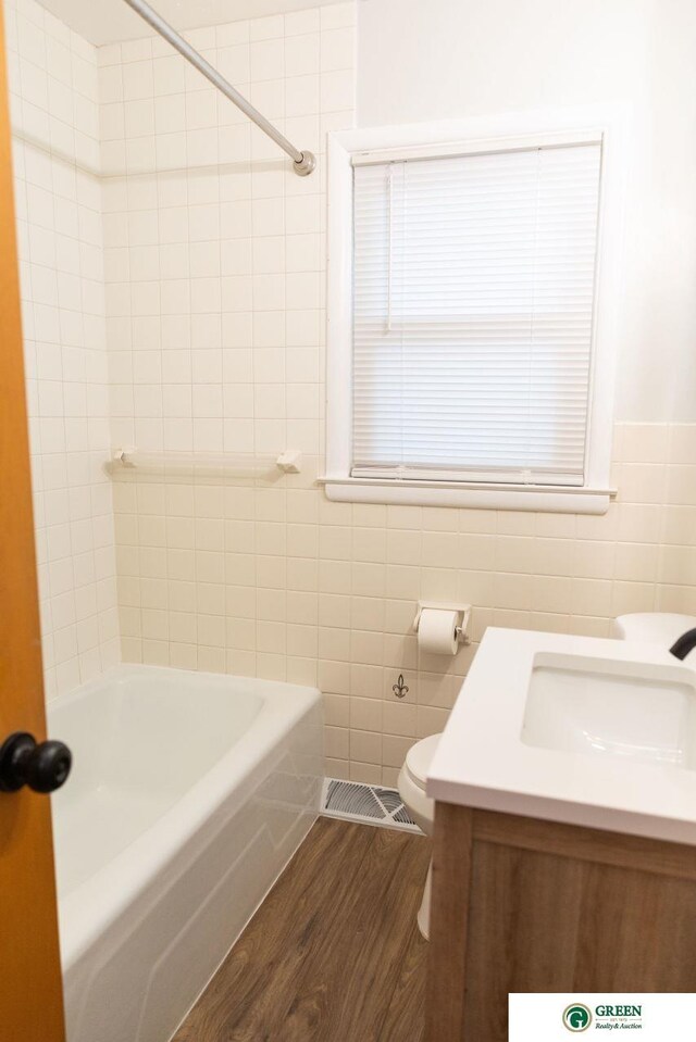 bathroom featuring vanity, wood finished floors, visible vents, tile walls, and toilet