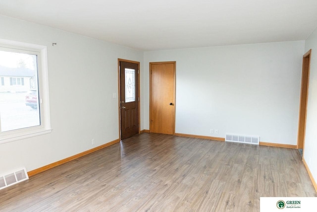 spare room featuring a wealth of natural light, visible vents, and light wood finished floors