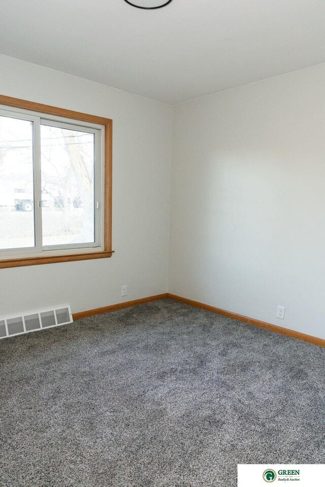 carpeted spare room featuring baseboards and visible vents