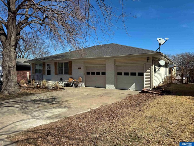 single story home with an attached garage, brick siding, driveway, and roof with shingles