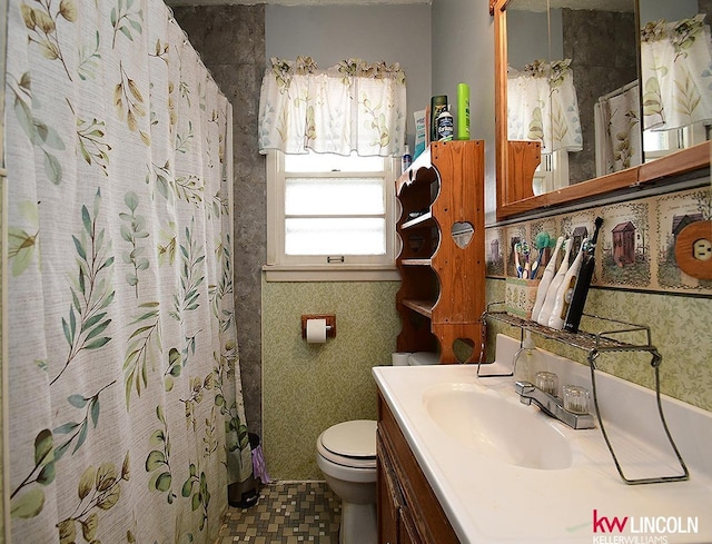 bathroom featuring toilet, vanity, and a shower with curtain