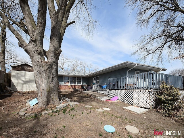 rear view of property featuring brick siding and a deck