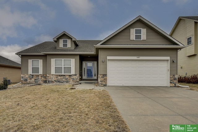 view of front of home featuring a front yard, central AC unit, concrete driveway, a garage, and stone siding