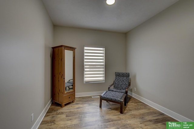 living area featuring visible vents, wood finished floors, and baseboards