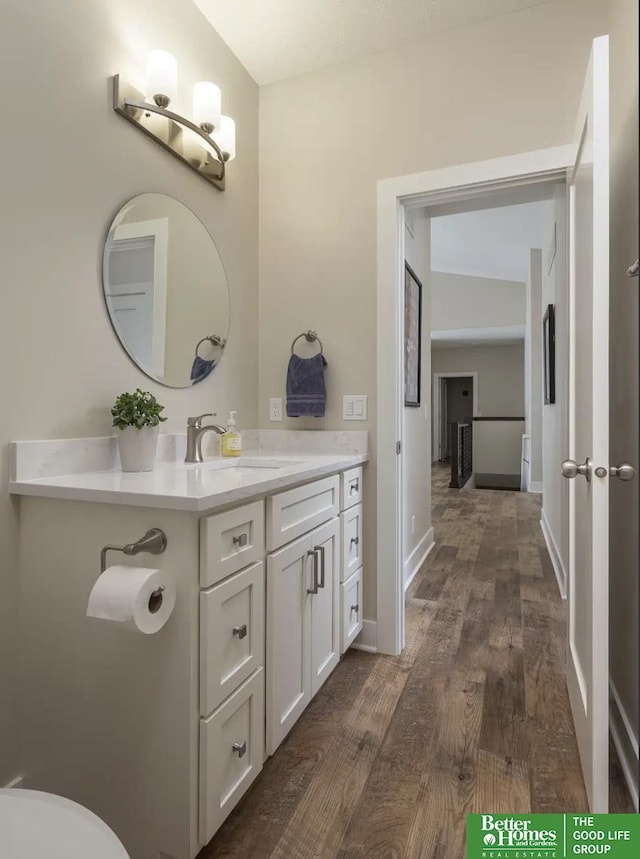 bathroom with baseboards, toilet, wood finished floors, and vanity