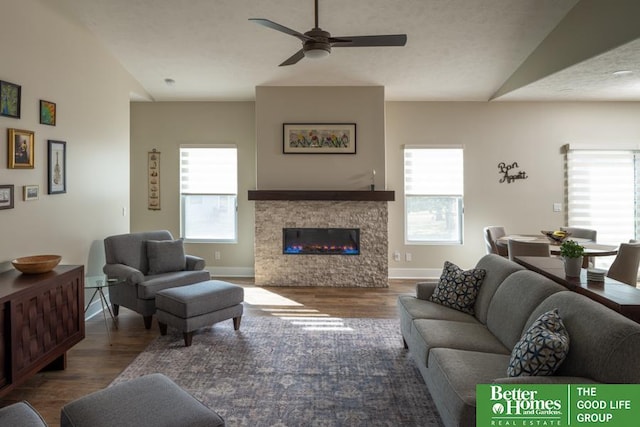 living room with a glass covered fireplace, ceiling fan, baseboards, and wood finished floors