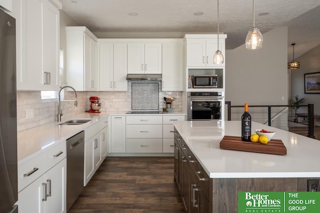 kitchen featuring a kitchen island, under cabinet range hood, light countertops, appliances with stainless steel finishes, and a sink