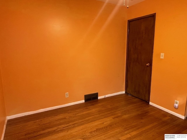 empty room featuring visible vents, baseboards, and wood finished floors