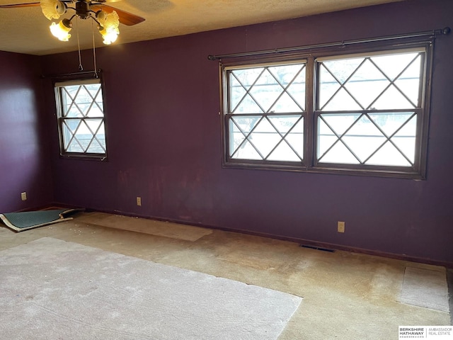 carpeted empty room featuring baseboards, visible vents, and a wealth of natural light