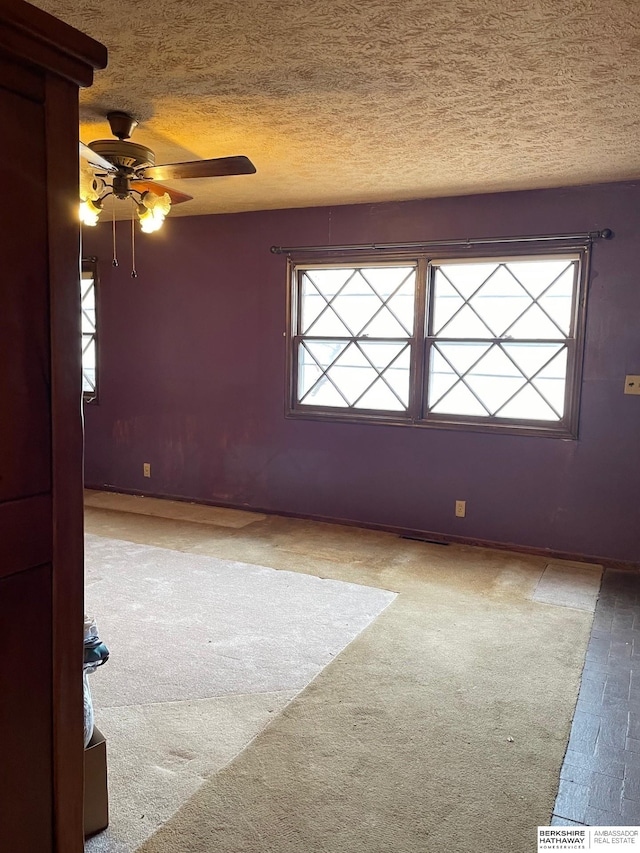 empty room featuring carpet floors, a textured ceiling, and a ceiling fan