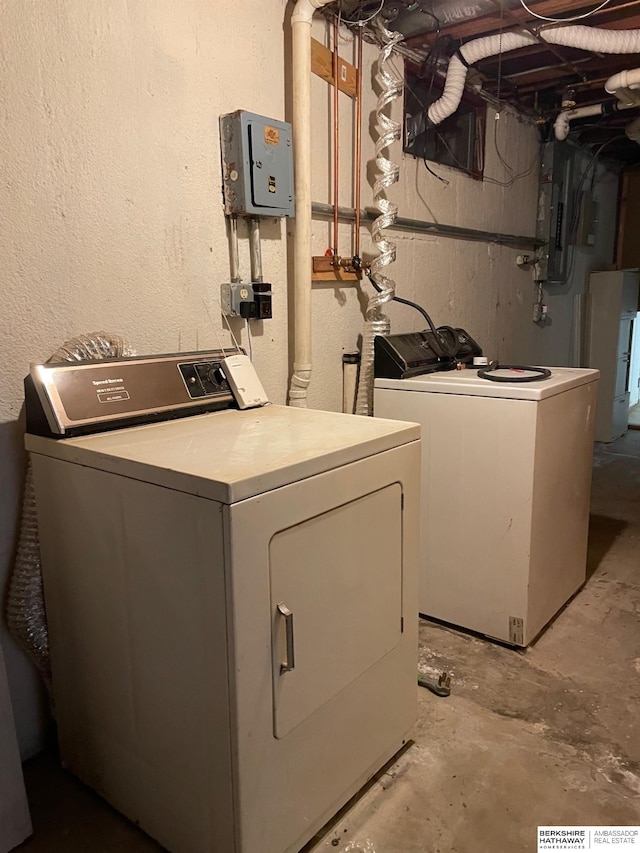 laundry room featuring electric panel, laundry area, washing machine and dryer, and a textured wall