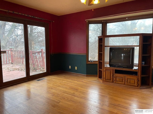 unfurnished living room with a wealth of natural light, visible vents, and light wood-style flooring