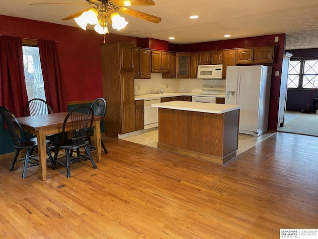 kitchen featuring white appliances, light wood-style flooring, light countertops, and a center island