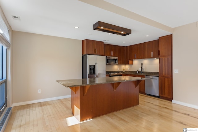 kitchen with a kitchen bar, light wood-style floors, visible vents, and appliances with stainless steel finishes