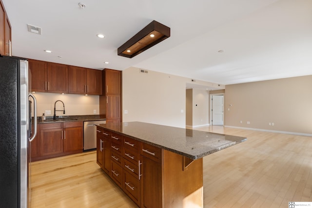 kitchen featuring visible vents, light wood finished floors, a kitchen island, a sink, and appliances with stainless steel finishes