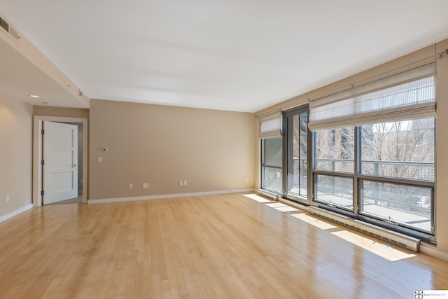 spare room featuring visible vents, light wood-type flooring, and baseboards