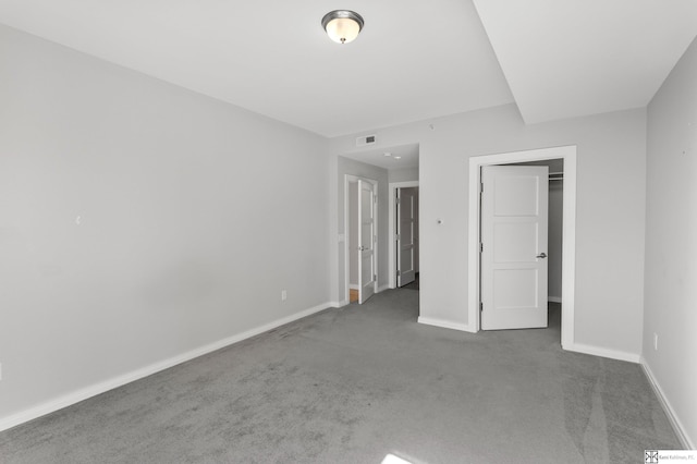 unfurnished bedroom with visible vents, baseboards, a spacious closet, and carpet flooring