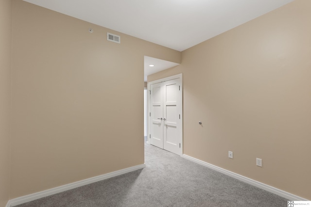 carpeted spare room featuring visible vents and baseboards