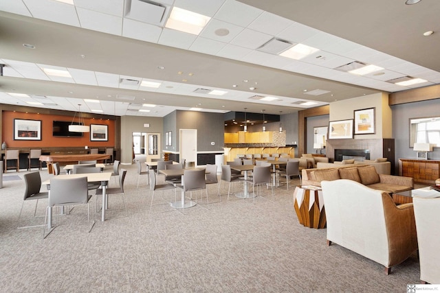 interior space with a drop ceiling, visible vents, and a glass covered fireplace