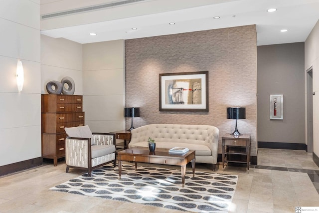 living area featuring an accent wall, recessed lighting, and baseboards