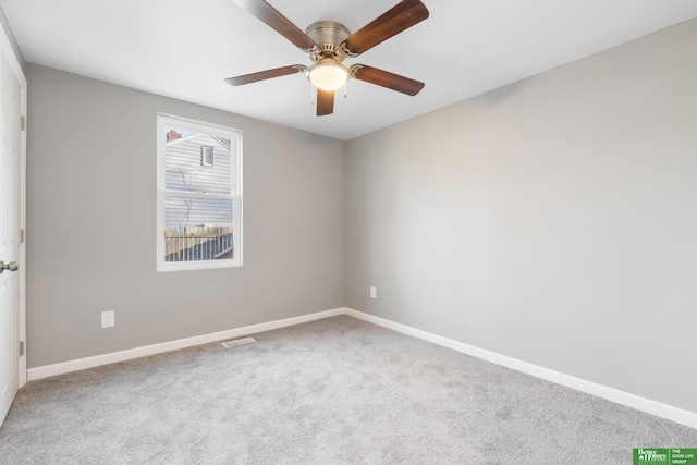 carpeted spare room featuring baseboards and a ceiling fan