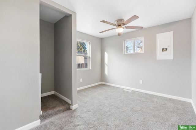 carpeted spare room featuring plenty of natural light, a ceiling fan, and baseboards