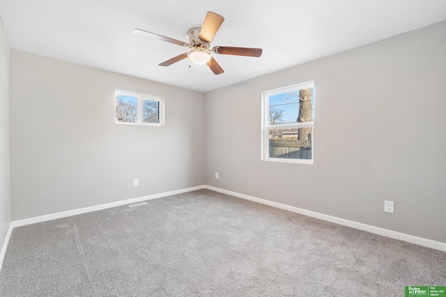 carpeted spare room featuring baseboards and a ceiling fan