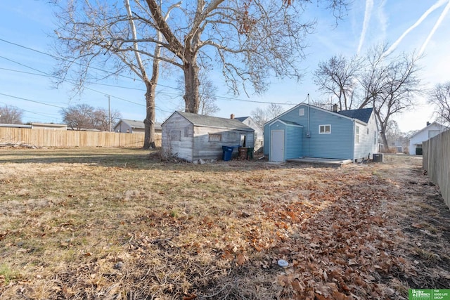 view of yard with an outbuilding, a storage unit, and fence