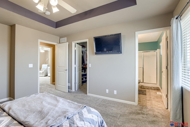 bedroom featuring carpet, visible vents, baseboards, a walk in closet, and a raised ceiling