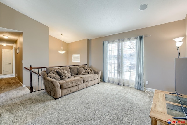 carpeted living area featuring baseboards and vaulted ceiling