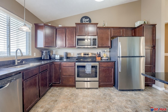 kitchen featuring pendant lighting, a sink, dark stone countertops, appliances with stainless steel finishes, and vaulted ceiling