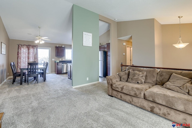 living room featuring light colored carpet, high vaulted ceiling, baseboards, and ceiling fan