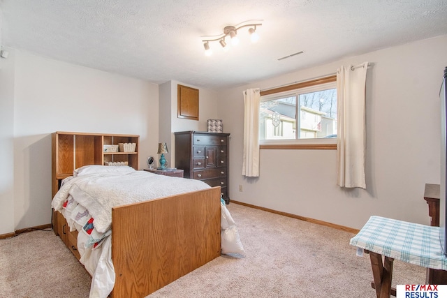 bedroom with baseboards, light carpet, a textured ceiling, and visible vents