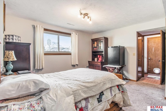 carpeted bedroom with a textured ceiling and baseboards