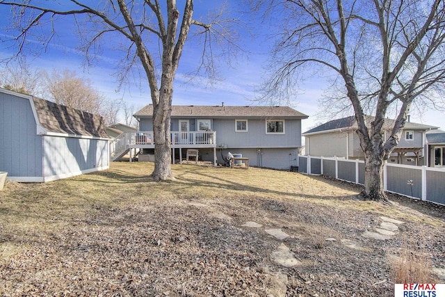 rear view of house with a wooden deck, an outbuilding, and a fenced backyard