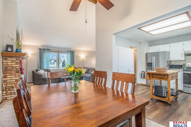 dining room featuring a high ceiling, ceiling fan, and wood finished floors