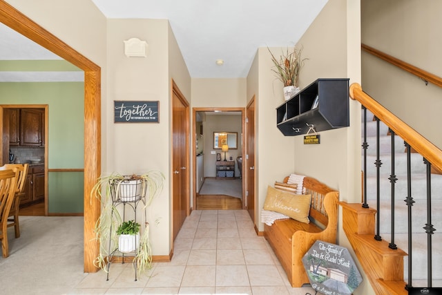 hallway featuring tile patterned floors, stairway, and baseboards