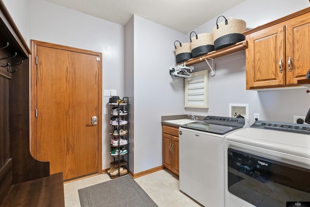 washroom featuring baseboards, washing machine and dryer, light tile patterned floors, cabinet space, and a sink