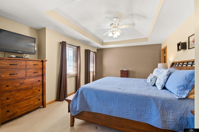 carpeted bedroom featuring a raised ceiling, a ceiling fan, and baseboards