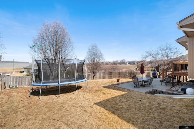 view of yard featuring a trampoline, a fenced backyard, and a patio area