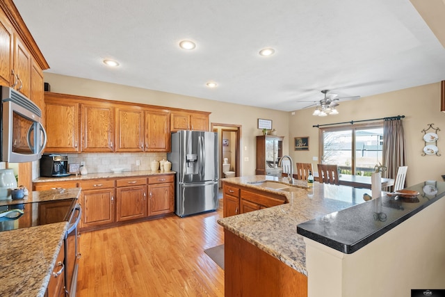 kitchen featuring tasteful backsplash, brown cabinets, appliances with stainless steel finishes, and a sink