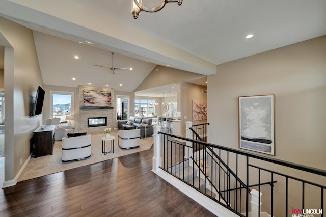 living area with wood finished floors, a fireplace, recessed lighting, vaulted ceiling, and ceiling fan with notable chandelier